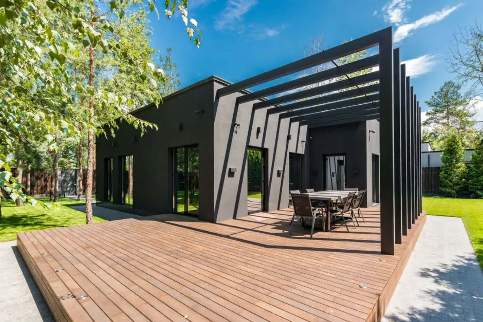 Pergola z antracitových profilů nad dřevěnou terasou rodinného domu