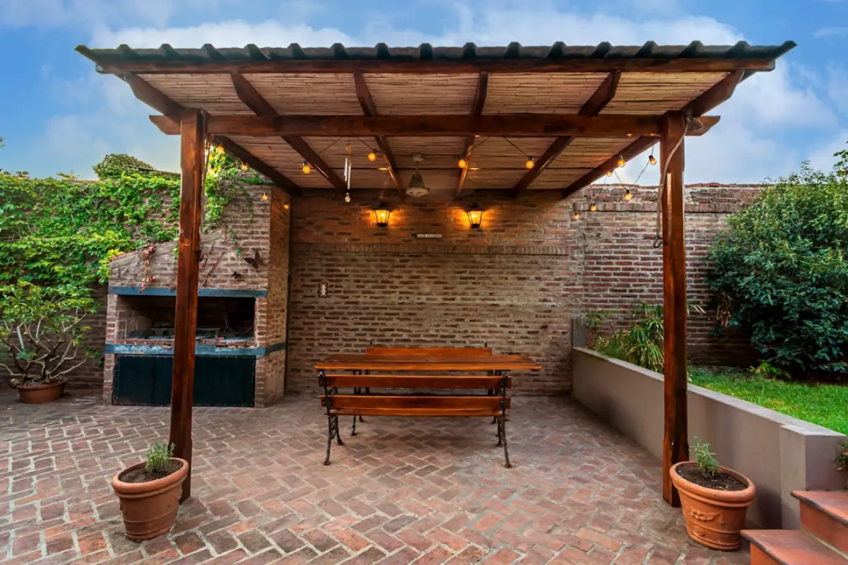 Dřevěná pergola s lavicí a cihlovou zdí na zahradě